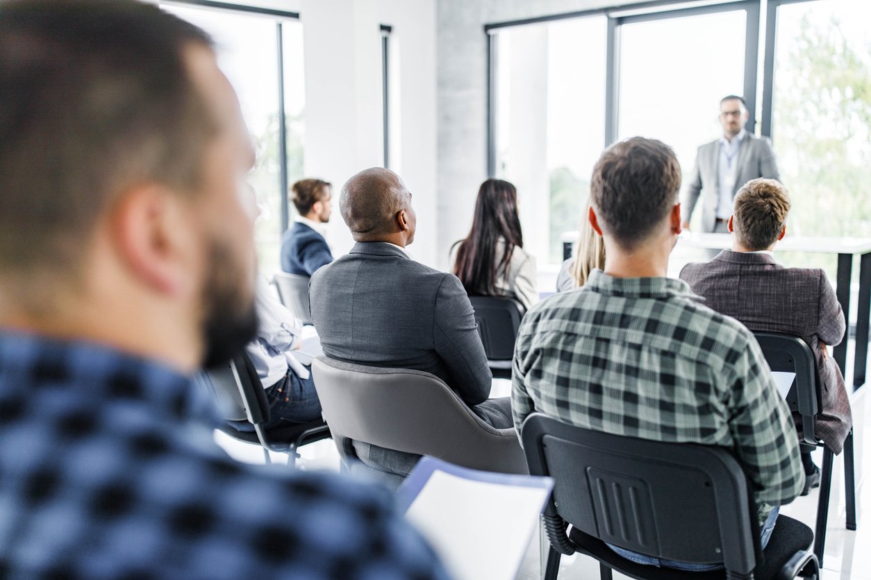 Rear view of business people having a seminar in board room.