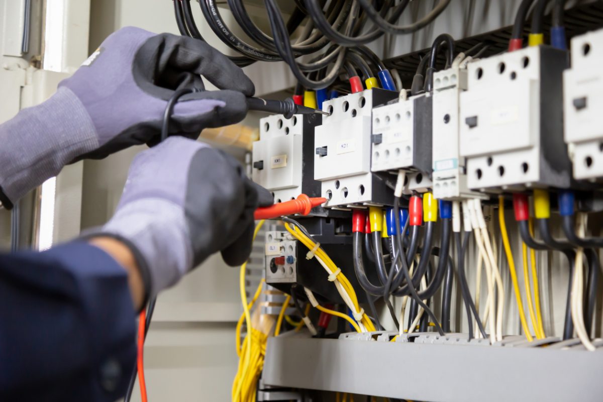 Electrician engineer tests electrical installations and wires on relay protection system. Adjustment of scheme of automation and control of electrical equipment.