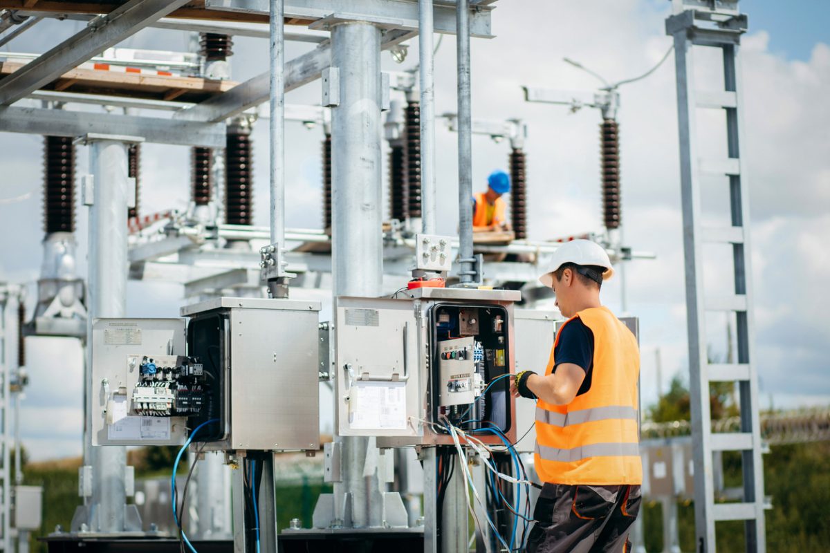 Adult electrical engineer mount the electrical systems at the equipment control cabinet. Installation of modern electrical station